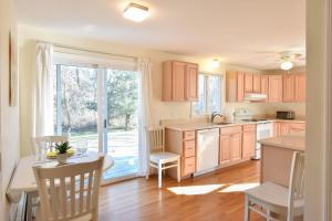 a kitchen with wooden cabinets and a table and a dining room at 14482 - Exceptional Home with Backyard Oasis Close to Great Pond Bay and Ocean Beaches in Eastham
