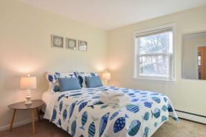 a bedroom with a blue and white bed and a window at 14482 - Exceptional Home with Backyard Oasis Close to Great Pond Bay and Ocean Beaches in Eastham