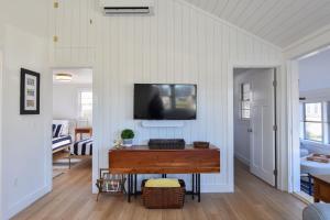 ein Wohnzimmer mit einem Tisch und einem TV an der Wand in der Unterkunft Newly Renovated Cottage on Town Cove in Eastham