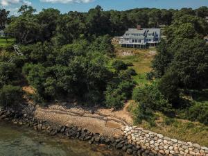 una vista aérea de una casa en una colina cerca del agua en 15526 - Luxurious Waterfront Home with Incredible Entertainment Space Secluded on Pleasant Bay, en Orleans