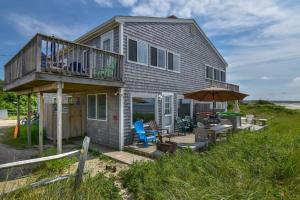 a house on the beach with a deck and an umbrella at Beachfront on Skaket Water Views in Orleans