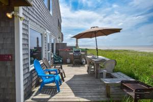 a wooden deck with chairs and an umbrella at Beachfront on Skaket Water Views in Orleans