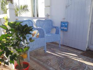 twee blauwe rieten stoelen op een veranda met een plant bij Villa Glen-Tara in Lanton