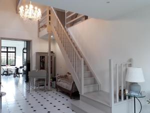 eine weiße Treppe in einem Wohnzimmer mit einem Kronleuchter in der Unterkunft Villa Glen-Tara in Lanton