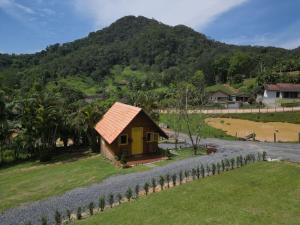 a small yellow house with a mountain in the background at Chalé do Vale Pomerode in Pomerode