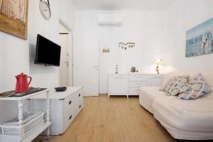 Il comprend un salon blanc doté d'un canapé et d'une télévision. dans l'établissement Bilocale via Rimembranze 6, à Levanto
