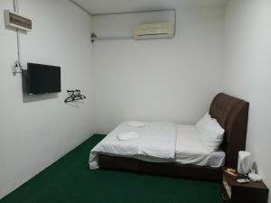 a small room with a bed and a television at HASD GUESTHOUSE PANGKOR in Pangkor