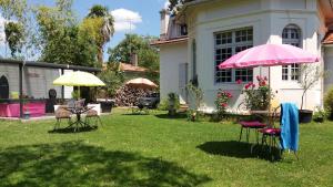 - une cour avec des chaises, des tables et un parasol rose dans l'établissement Villa Glen-Tara, à Lanton