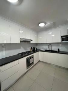 a kitchen with white cabinets and a stove top oven at 3 Bedroom House Ideal for Family - Ultimo in Sydney