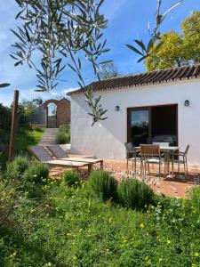 un patio con mesa y sillas frente a una casa en La colina buena - Eco retreat, en Monda