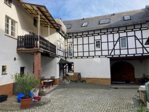 a courtyard of a large white building with a balcony at Pension und Ferienwohnung am Teich in Schleiz