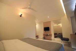 Hotel Shoolin Grand في منغالور: غرفة نوم بسرير وتلفزيون وكرسي