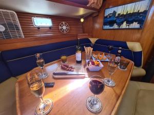 una mesa de madera con copas de vino y comida. en Coriandre 2 - Dormir sur un grand voilier 9 personnes By Nuits au Port, en La Rochelle