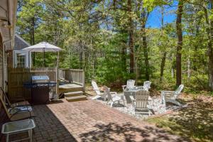 Un patio con sillas, una mesa y una sombrilla. en 5-Mins to Forest Beach Dog Friendly, en Chatham