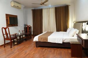 a hotel room with a bed and a table and a desk at Malanadu Tourist Home in Hosdrug