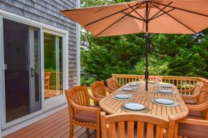 una mesa de madera con una sombrilla en la cubierta en Spacious w Beautiful Yard & Dogs Welcome, en Harwich