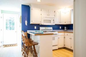 a kitchen with white cabinets and a blue wall at Full Sand Volleyball Court Walk to Pond in Brewster +33 photos