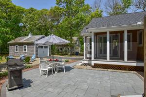 a patio with a table and chairs and a house at Spacious Home by Beach Dog Welcome in Brewster