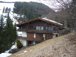una casa en la cima de una colina con nieve en Appartement Bernkogel, en Saalbach Hinterglemm