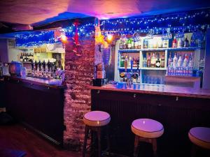 a bar with two stools at a bar with blue lights at BEAR INN - BISLEY in Bisley