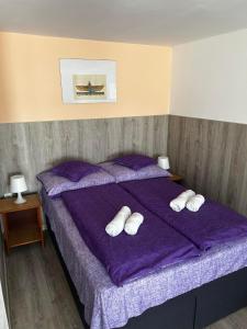 a purple bed with three white pillows on it at Apartment R&eacute;v&eacute;sz in Hark&aacute;ny