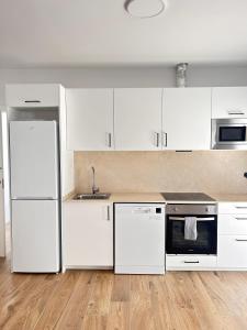 a white kitchen with white cabinets and appliances at Benicasim Village in Benicàssim