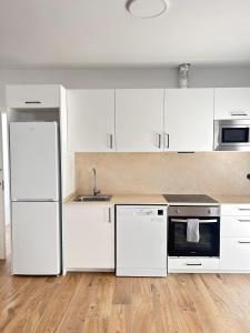 a white kitchen with white cabinets and appliances at Benicasim Village by Tucasanlaplaya in Benicàssim