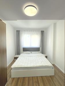 een witte slaapkamer met een groot bed en een raam bij City Center 1bedroom in Ferizaj