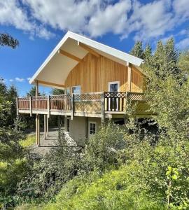 a house with a wrap around deck in the woods at Forest Hideaway Near Akureyri in Akureyri