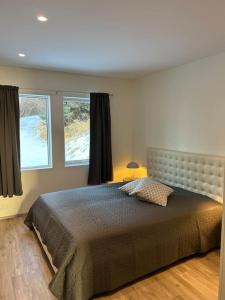 a bedroom with a large bed and two windows at Forest Hideaway Near Akureyri in Akureyri