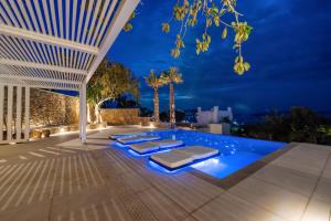 a patio with a pool at night at Numi Suites in Mikonos