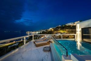 a balcony with a swimming pool at night at Tagoo Hills Residences in Mikonos
