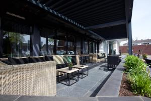 eine Terrasse mit Sofas und Tischen auf einem Gebäude in der Unterkunft Hotel Arrows in Uden