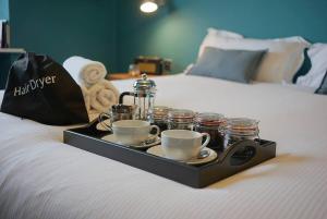 a tray with cups and saucers on a bed at The Alma Taverns Boutique Suites - Room 5 - Hopewell in Bristol