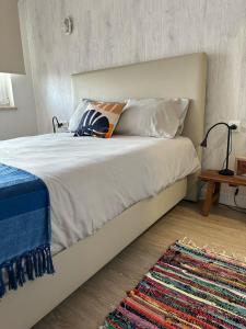Una cama con sábanas blancas y una almohada naranja. en BerlengaBed&Breakfast en Peniche