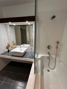 uma casa de banho com um lavatório, uma banheira e um espelho. em Bungalow Terra - Sarramea em Sarraméa