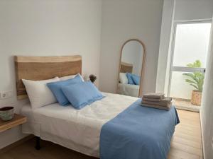 een slaapkamer met een bed met blauwe kussens en een spiegel bij El rincón de Regina in Córdoba