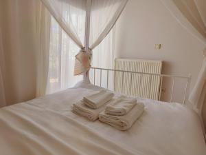 1 cama con 3 toallas y ventana en Artemis Cinema Garden Near Airport & Sea en Loútsa