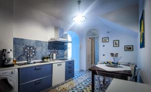 una cocina con armarios azules y una mesa. en Villa Angelina, en Vietri