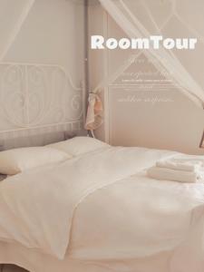 a bedroom with a bed with white sheets and a room sign at Artemis Cinema Garden Near Airport & Sea in Artemida