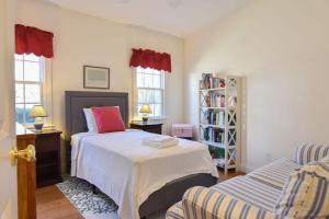a bedroom with a bed and a couch and two windows at Water Views & Private Tennis Court in Barnstable