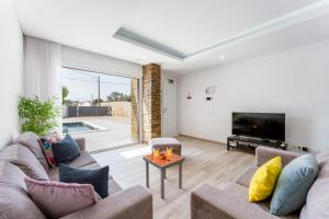 Una sala de estar con un sofá y un televisor. en Villa Almargens, en São Brás de Alportel