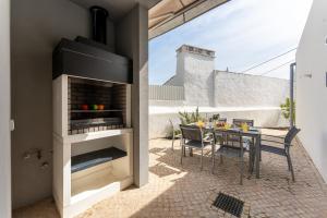 eine Terrasse mit einem Kamin und einem Tisch mit Stühlen in der Unterkunft Villa Almargens in São Brás de Alportel