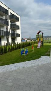 a playground with play equipment in front of a building at Apartament Pastelove Żywiec in Żywiec