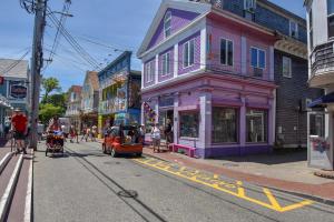 a small car driving down a street in a town at Rare Location on Commercial Street Exclusive Deck in Provincetown