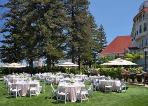 a group of tables with white chairs and umbrellas at Hotel del Coronado, Curio Collection by Hilton in San Diego