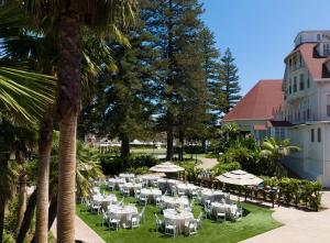 un restaurante con mesas blancas, sombrillas y palmeras en Hotel del Coronado, Curio Collection by Hilton, en San Diego