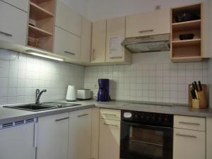 uma cozinha com armários brancos e um forno com placa de fogão em Ferienwohnung LVC11 em Graal-Müritz
