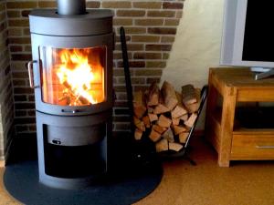 a stove with a fire in it next to a brick wall at Ferienhaus Waldwinkel in Wrexen