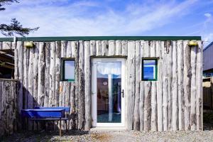 um edifício de madeira com uma porta e um banco azul em Retro Caravans at Valentia Island Escape em Valentia Island